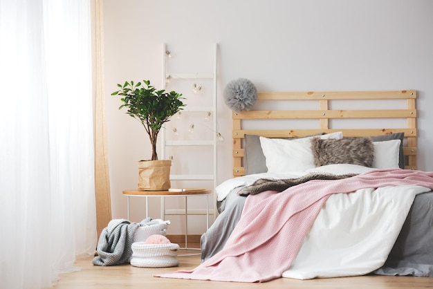 Un dormitorio con una cama y una planta al lado.