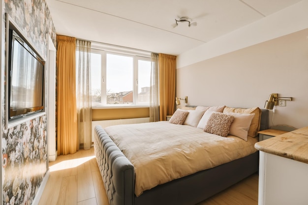 Un dormitorio con una cama y un televisor en la pared de la esquina visto desde la ventana