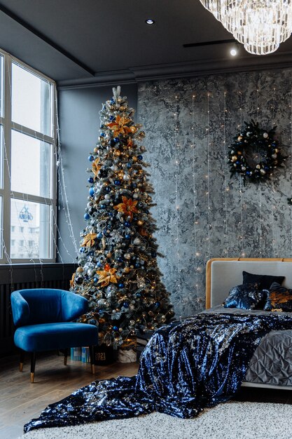 Dormitorio en colores oscuros con guirnalda y árbol de Navidad decorado