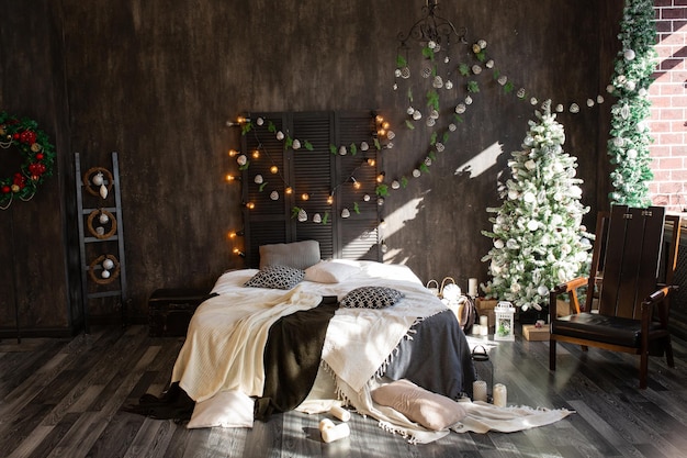 El dormitorio decorado por Navidad Acogedor interior oscuro cama y silla de madera a cuadros En la habitación hay un abeto de Año Nuevo decorado con juguetes y guirnaldas