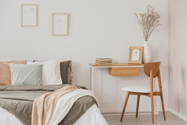 Un dormitorio con un escritorio y una silla con un jarrón de flores.