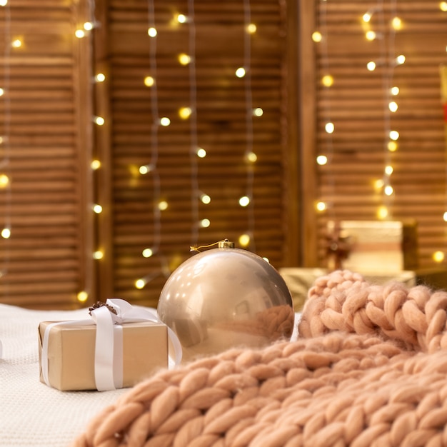 El dormitorio está decorado para Navidad. la cama está cubierta con una manta de punto grande Merino de diseño suave. las paredes están decoradas con luces de guirnaldas. ambiente agradable y acogedor de la Logia del amor