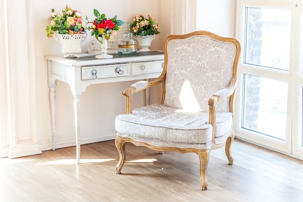 Foto dormitorio interior blanco clásico de lujo en estilo barroco con ventana grande, sillón y flores