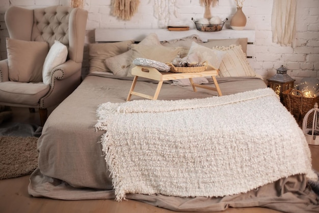 Dormitorio interior interior escandinavo con sillón y cama con una mesita en la cama y almohadas