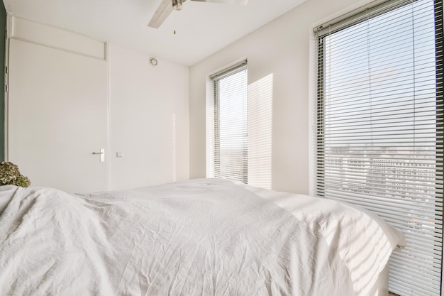 Dormitorio luminoso con puerta de ventilador de dos ventanas y pared blanca
