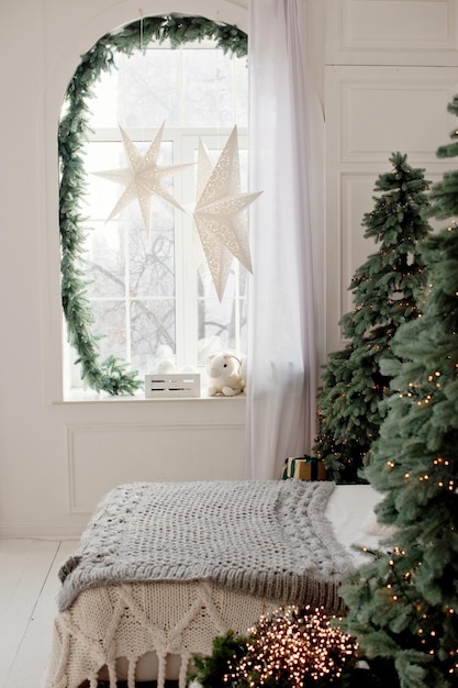 Dormitorio navideño con adornos de estrellas de árboles de Navidad en una ventana y acogedoras luces navideñas