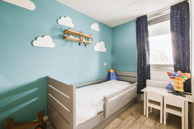 Foto el dormitorio de un niño con nubes en la pared.