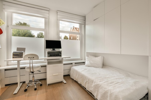 Dormitorio en tonos blancos con un lugar de trabajo y una computadora cerca de la ventana en una casa moderna