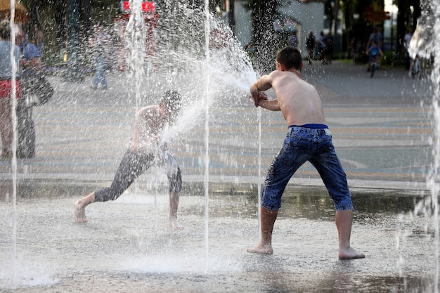 Dos adolescentes, juego, con, agua, en, fuente