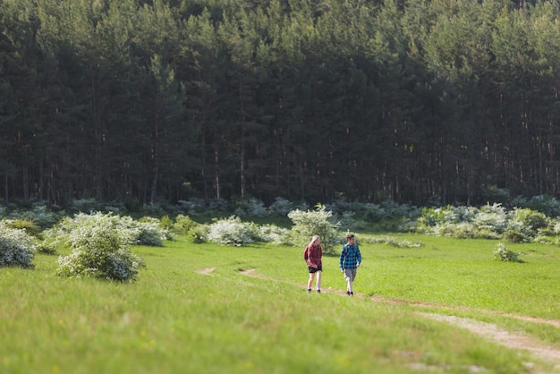 Dos adolescentes una niña y un niño caminan explorando y disfrutando de la belleza de la naturaleza rural en un