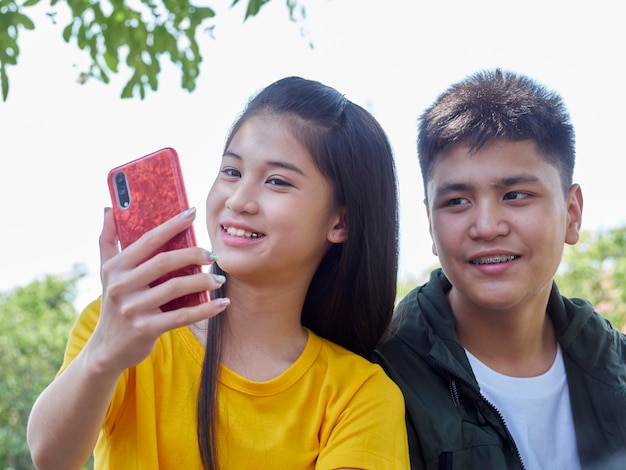 Dos adolescentes usan sus teléfonos inteligentes al aire libre