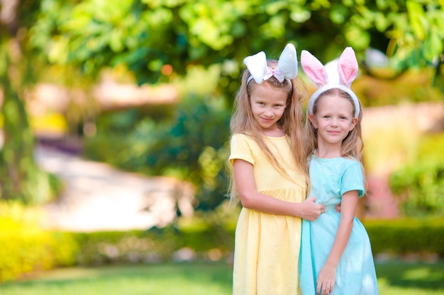 Dos adorables hermanitas con orejas de conejo en el día de Pascua al aire libre