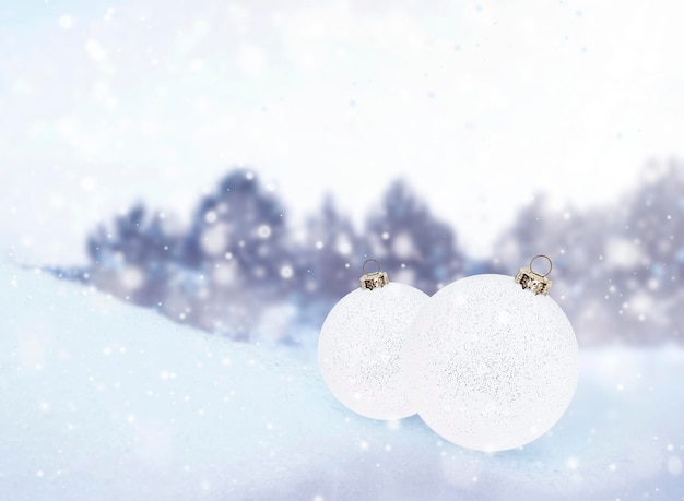 Dos adornos navideños blancos en la nieve con el telón de fondo de un bosque invernal