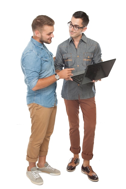 Dos alegre joven discutiendo algo en la computadora portátil y sonriendo