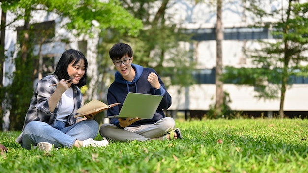 Dos alegres jóvenes estudiantes universitarios asiáticos se regocijan y celebran la puntuación de su examen