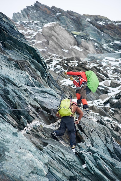 Dos alpinistas escalando montaña rocosa