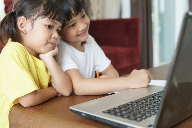 Dos alumnas asiáticas estudian en línea con el maestro por videollamada juntos.