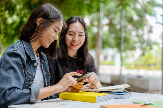 Dos alumnas utilizaban un teléfono para buscar información sobre sus estudios Libros de conocimientos