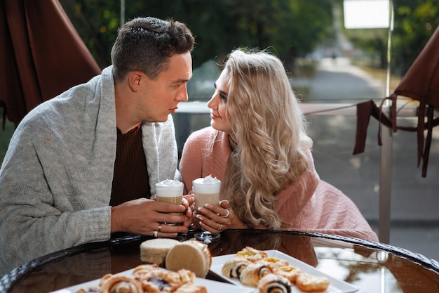Dos amantes, un hombre y una mujer en una mesa en un café. Abrazo, caricia, bebe café con leche. Feliz pareja tradicional, felicidad familiar.