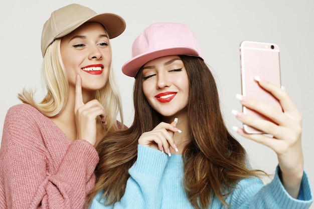 Dos amigas adolescentes en traje hipster hacen selfie en smar