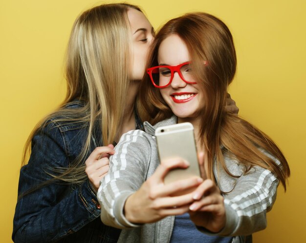 Dos amigas adolescentes en traje de hipster hacen selfie en un teléfono