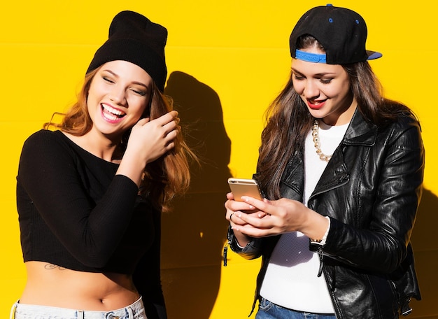 Dos amigas adolescentes vestidas de hipster al aire libre hacen selfie en un teléfono