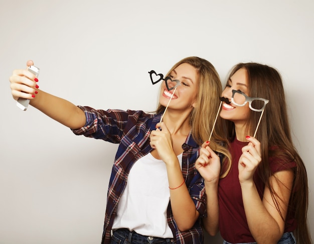 Dos amigas adolescentes vestidas de hipster hacen selfie en un teléfono.