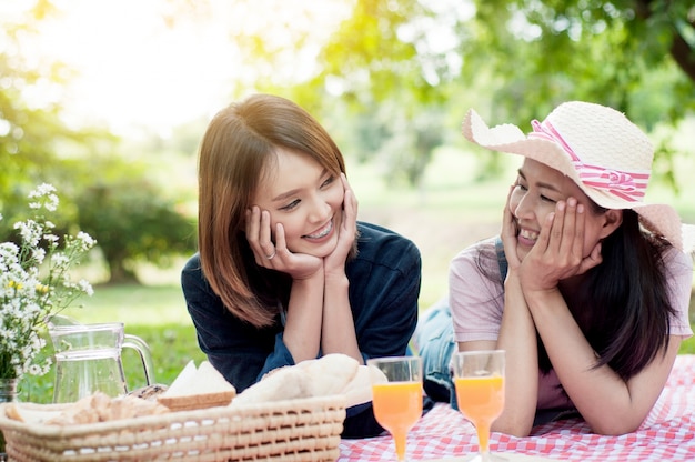 dos amigas asiáticas tirado en el césped, mujeres en el parque durante el día con picnic