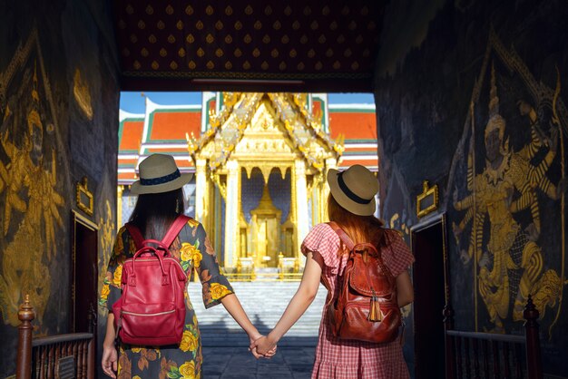 Dos amigas asiáticas viajan y pasan la puerta de entrada al gran palacio