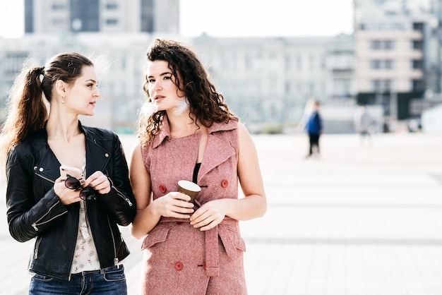 Dos amigas atractivas se comunican en la plaza de la ciudad