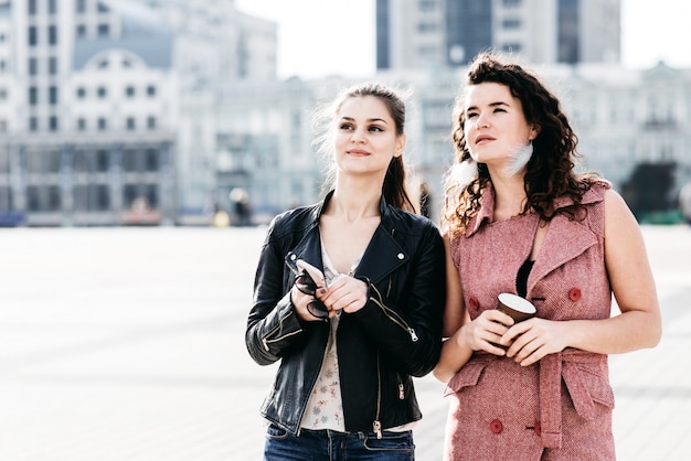 Dos amigas atractivas se comunican en la plaza de la ciudad