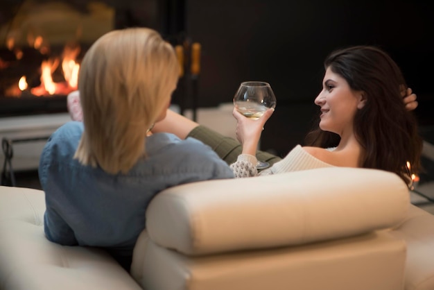 dos amigas bebiendo vino y hablando junto a una chimenea. concepto de estilo de vida