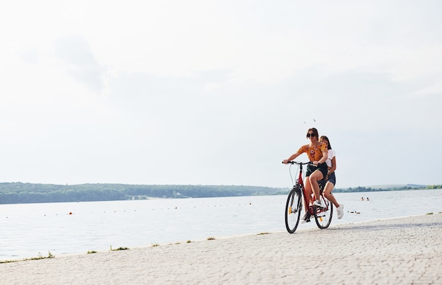 Dos amigas en bicicleta se divierten en la playa cerca del lago.