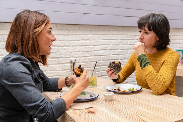 Dos amigas comiendo hamburguesas veganas en un restaurante