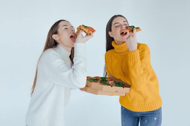 Dos amigas comiendo pizza.