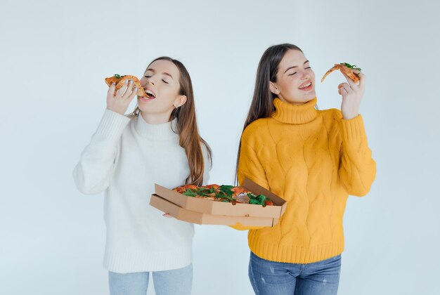 Dos amigas comiendo pizza.