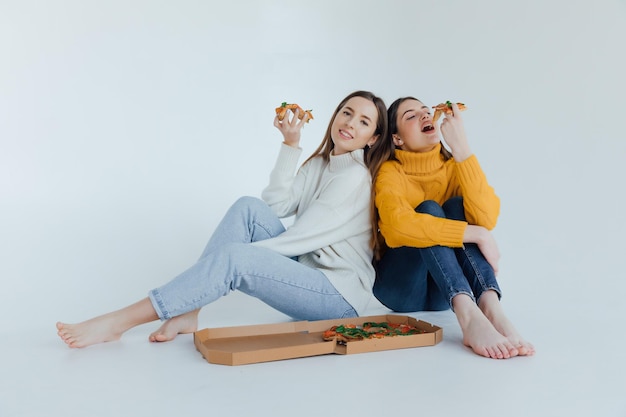 Dos amigas comiendo pizza.