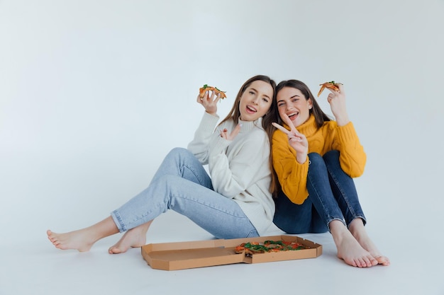 Dos amigas comiendo pizza.