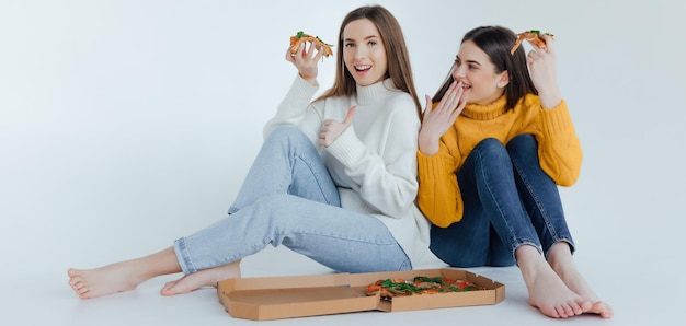 Dos amigas comiendo pizza.