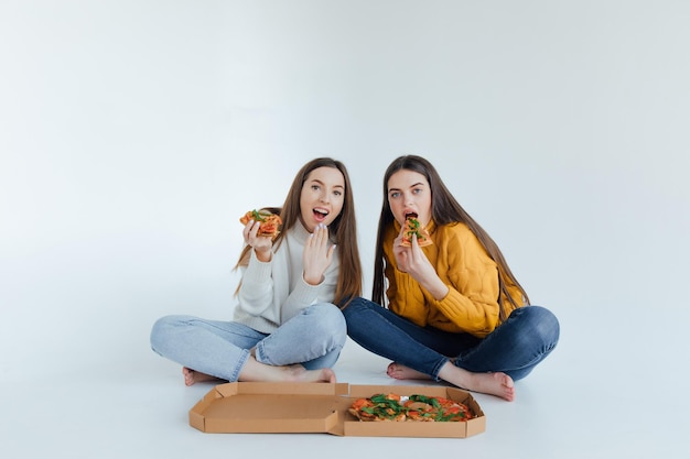 Dos amigas comiendo pizza.