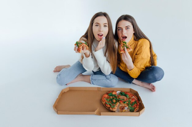 Foto dos amigas comiendo pizza.