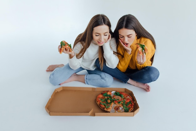 Dos amigas comiendo pizza.