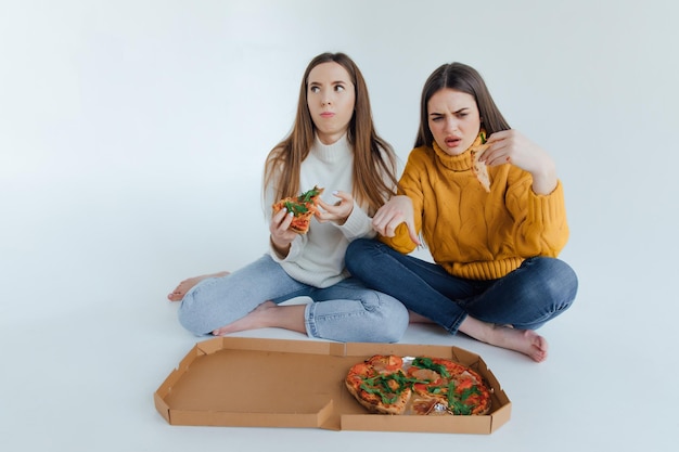 Dos amigas comiendo pizza.