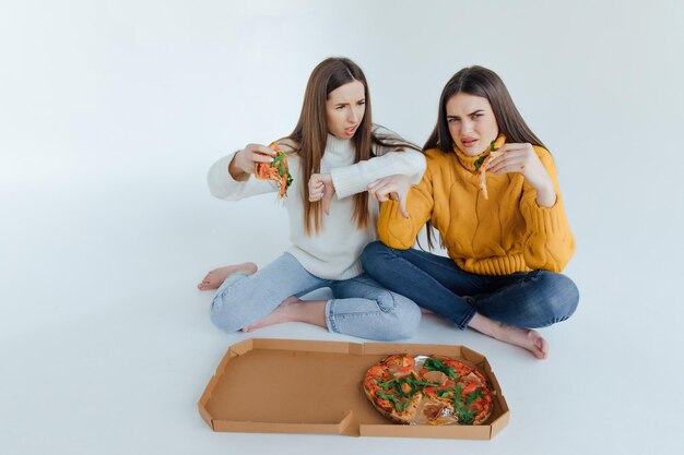 Dos amigas comiendo pizza.