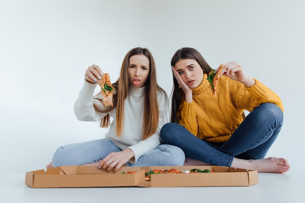 Dos amigas comiendo pizza.