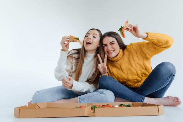 Dos amigas comiendo pizza.