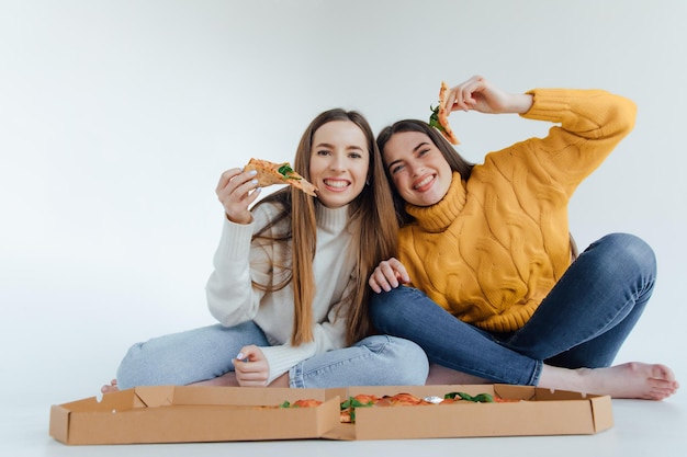 Dos amigas comiendo pizza.