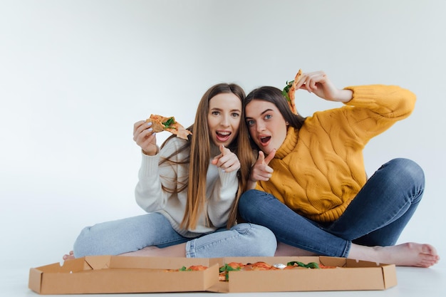 Dos amigas comiendo pizza.