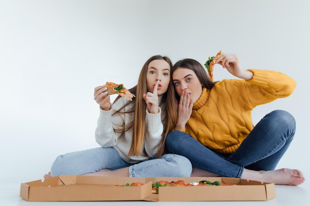 Foto dos amigas comiendo pizza.