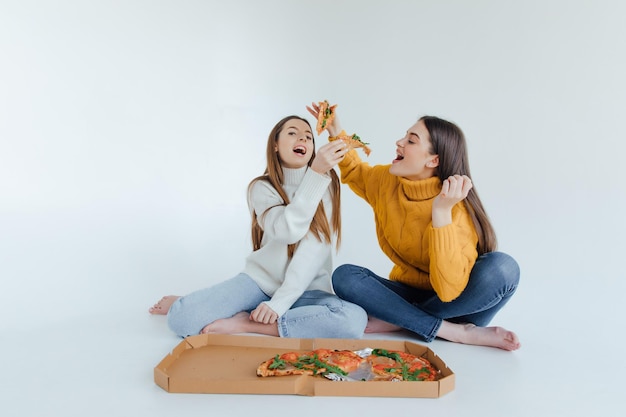 Dos amigas comiendo pizza.